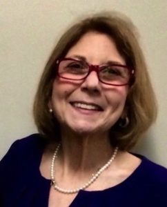 Image of Marcie Roth wearing Red glasses , head titilted, smiling.